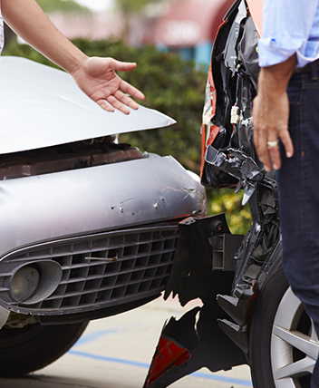 Two people discussing damage after a car accident, representing auto insurance services.