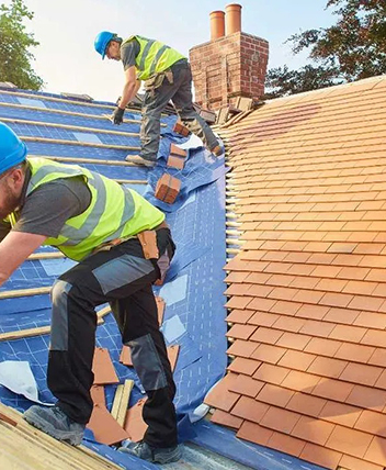 Professional workers installing shingles on a house roof.