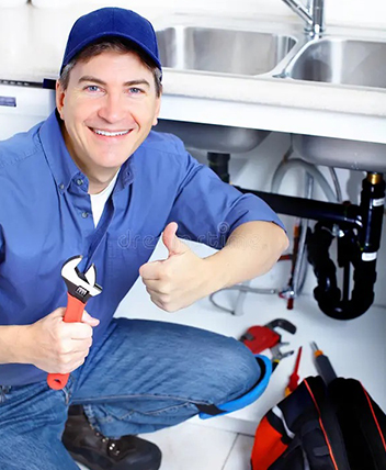 Smiling plumber giving thumbs up while fixing a sink pipe.