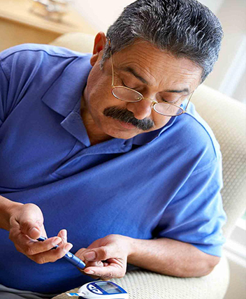 Elderly man checking blood sugar level at home.