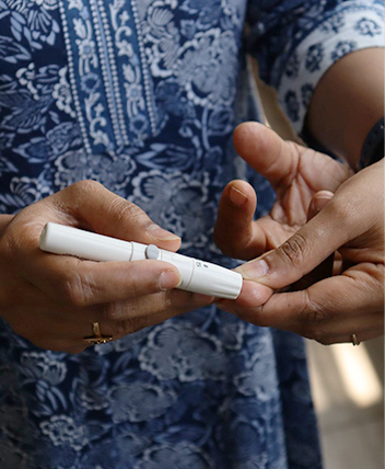 Person checking blood sugar with a lancet device for diabetes management.