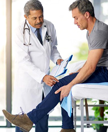 Doctor examining patient’s injured leg during a medical consultation.